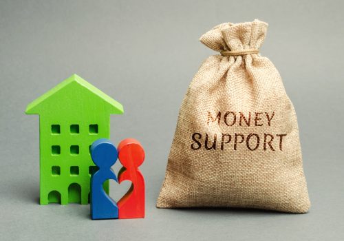 Family standing near the house with a bag with the word Money support